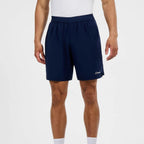 A person wearing navy athletic shorts with a white Berghaus logo on the lower left hem, paired with a white top and white socks, shown against a light gray studio background.