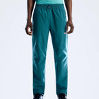 A person wearing teal Berghaus pants with an elastic drawstring waist and a small white logo on the left thigh, shown against a light gray studio background.