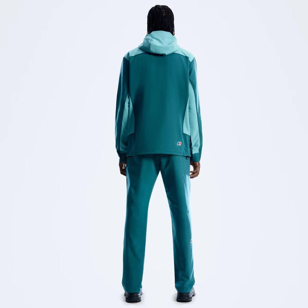 A model viewed from behind wearing a Berghaus teal and mint green hooded jacket and matching pants against a plain white studio background.