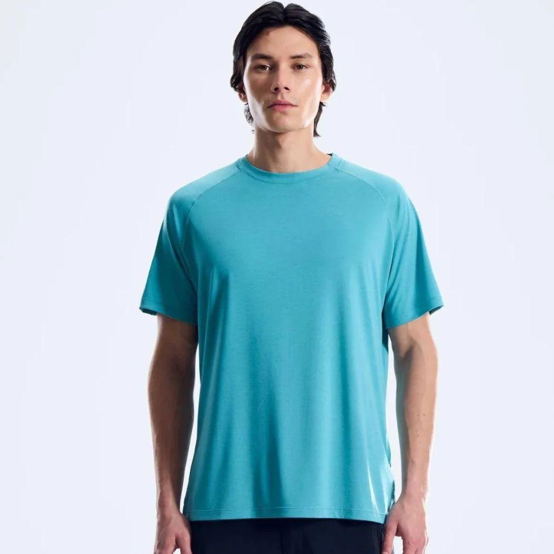 A man wearing a short-sleeve athletic t-shirt in a vibrant teal color, standing against a plain white studio background.
