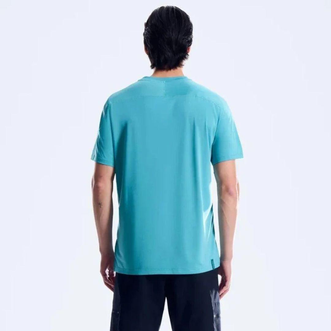 A man viewed from behind wearing a short-sleeve athletic t-shirt in a vibrant turquoise blue color, paired with black pants, against a clean white studio background.
