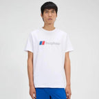 A man wearing a white crewneck t-shirt with a blue and red Berghaus logo on the chest, paired with blue shorts, against a light gray studio background.