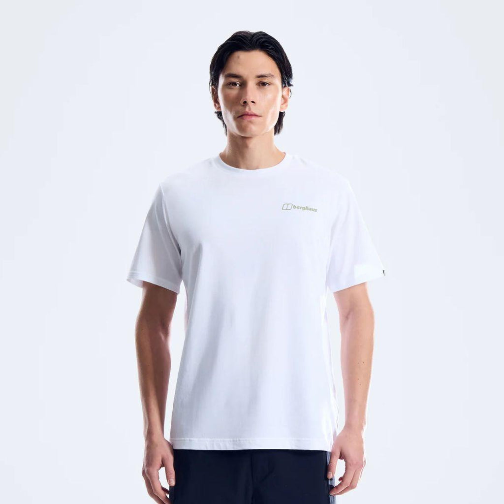 A man wearing a white short-sleeve crewneck t-shirt with a small gold Berghaus logo on the left chest, paired with dark pants, against a plain white studio background.