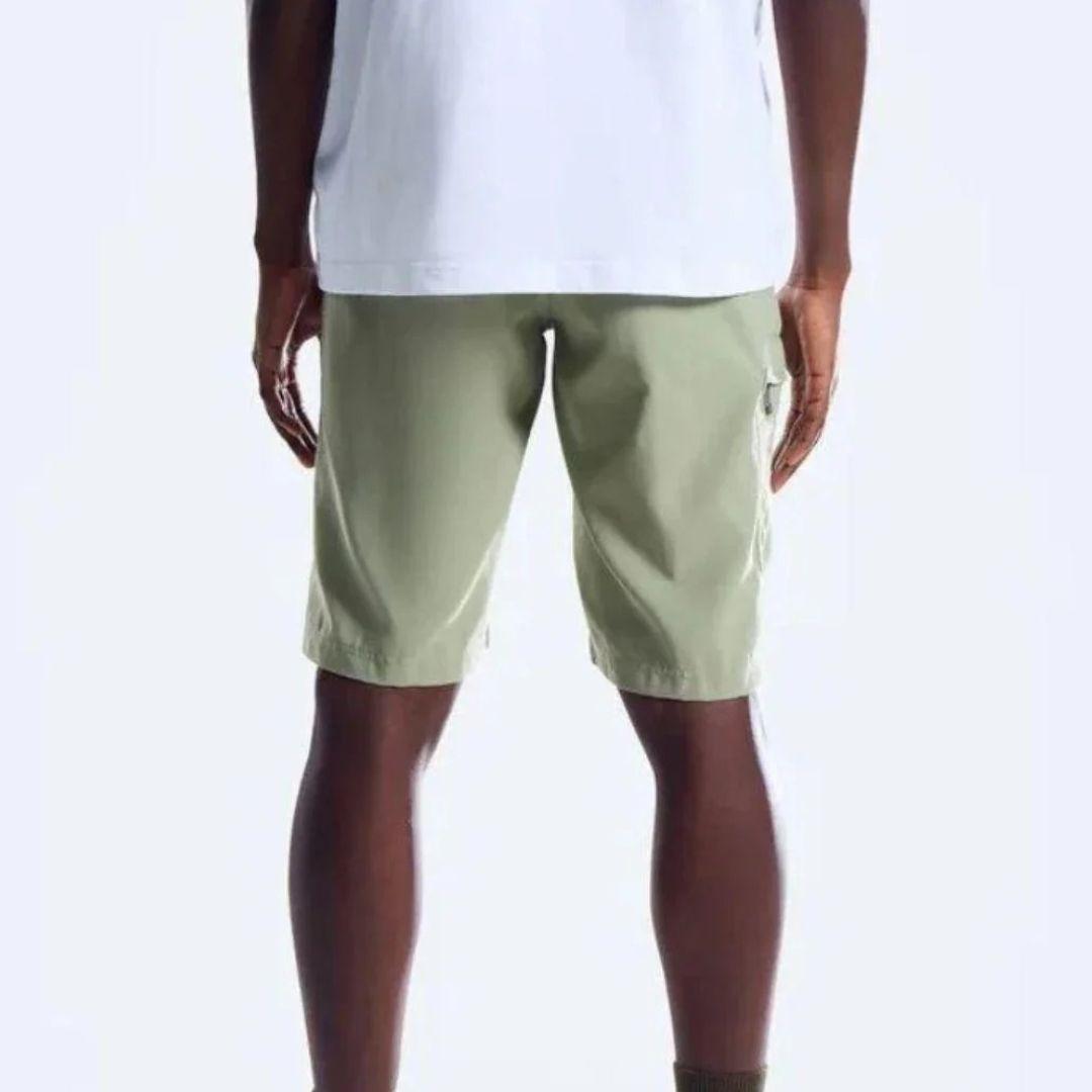 A person wearing light sage green cargo shorts and a white t-shirt, shown from the chest down against a plain white background.