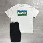 A white short-sleeve crewneck t-shirt with a Berghaus graphic on the chest, laid flat on a gray textured background next to a pair of black pants.