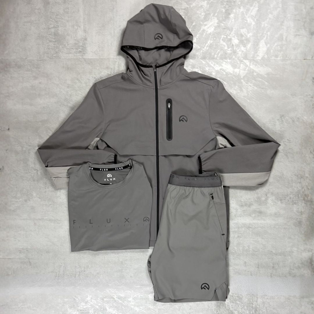 Flux Grey athletic jacket, shirt, and shorts set on a textured gray surface