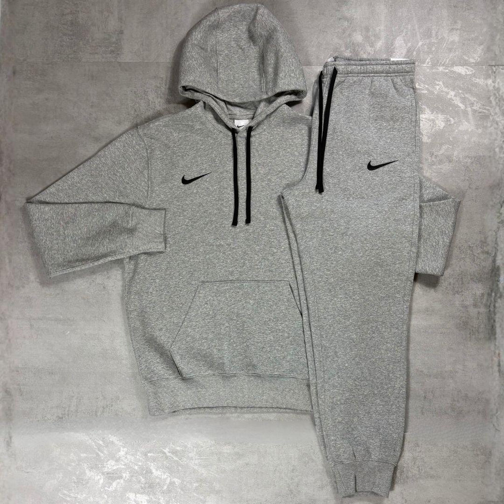 Nike Grey Club Fleece Hoodie and Joggers Tracksuit for men, flat lay of marl grey cotton fleece pullover hoodie with drawcord hood and kangaroo pocket and matching cuffed joggers with black Nike swoosh