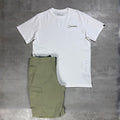 A white short-sleeve crewneck t-shirt with a small black Berghaus logo on the left chest, laid flat next to a pair of olive green cargo shorts on a textured gray concrete background.